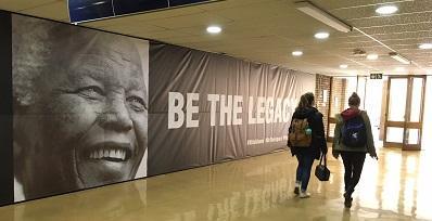 足球竞彩app排名s walk past the Nelson Mandela 100 memorial banner wall